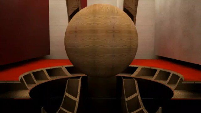 Video Reference: wooden sphere, abstract, industrial interior, symmetry, stage, metal supports, geometric, centered composition, sculpture, installation, red floor, artificial lighting