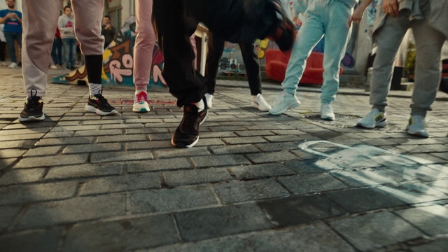 Video Reference: Footwear, Trousers, Shoe, Leg, Road surface, Thigh, Street fashion, Interaction, Sneakers, Public space