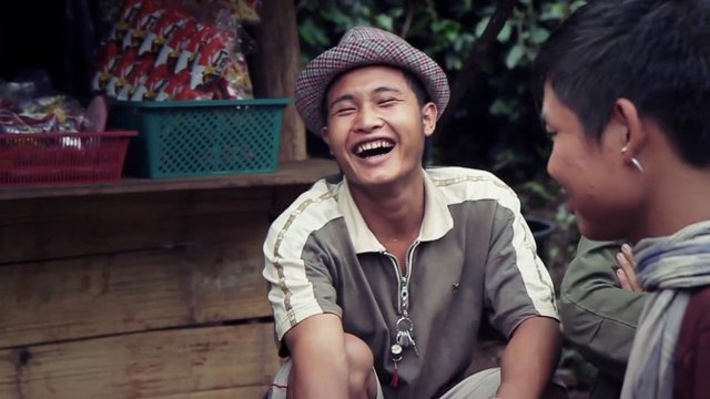 Video Reference: outdoors, young men, laughing, conversation, market, stall, casual, smiling, portrait, street scene, wooden background, social interaction