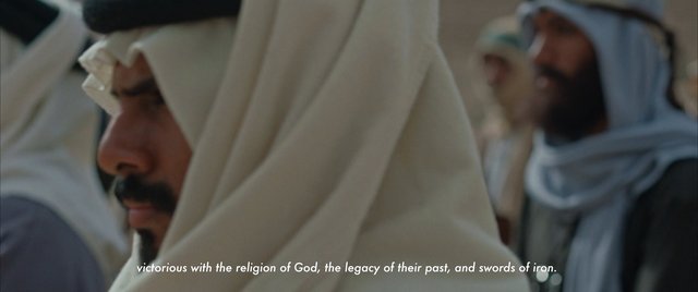 Video Reference: men, traditional clothing, head covering, close-up, crowd, indoor, soft focus, religious, cultural, subtitle, profile, portrait, group, neutral background