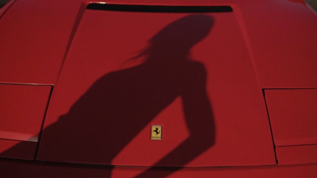 Video Reference: sports car, car hood, red, Ferrari, emblem, shadow, silhouette, automotive, luxury car, close-up, reflection, motion, vehicle, hood, dramatic lighting