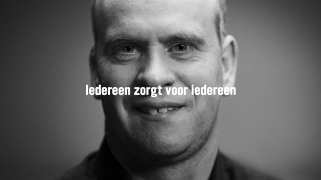 Video Reference: portrait, man, smiling, black and white, close-up, face, text overlay, Dutch, studio lighting, human, headshot, monochrome