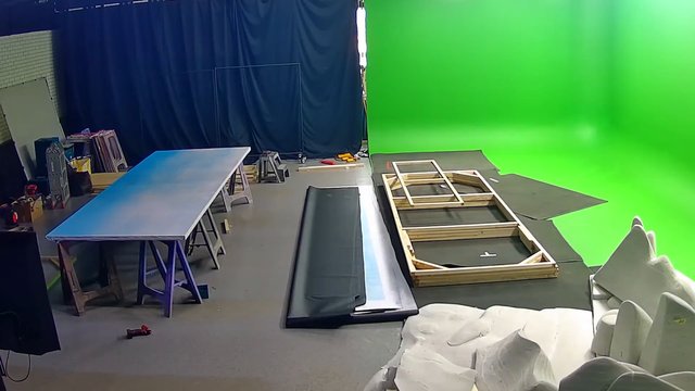 Video Reference: indoor studio, green screen, film set, production, backdrop, props, wooden frame, worktable, curtains, set construction, studio floor, equipment, workspace