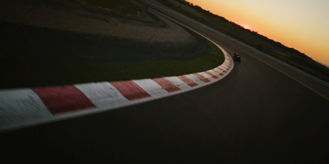 Video Reference: racetrack, motorcycle, track, curve, sunset, speed, motion blur, asphalt, racing, outdoor, evening, sports, circuit, corner