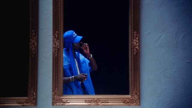 Video Reference: Blue, Sleeve, Window, Headgear, Rectangle, Tints and shades, Electric blue, Wood, Curtain, Glass
