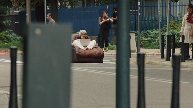 Video Reference: street, man, laptop, chair, pedestrian, urban, outdoor, crosswalk, fence, city, walking, middle-aged, road, public