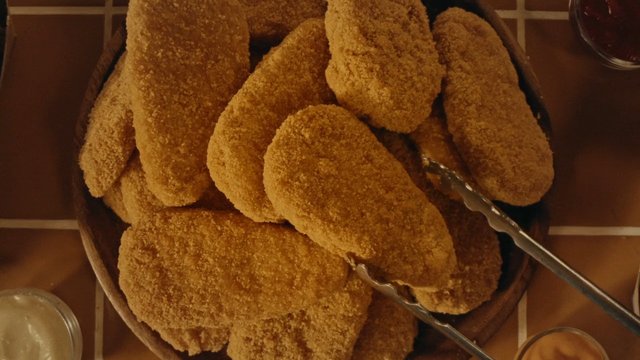 Video Reference: food, fried food, breaded, bowl, tongs, table, close-up, snack, appetizer, cooking, restaurant, meal, sauce
