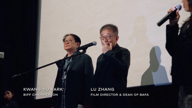 Video Reference: stage, public event, panel, microphone, speakers, presentation, conference, indoor, audience event, men, woman, on-screen text, formal attire, discussion