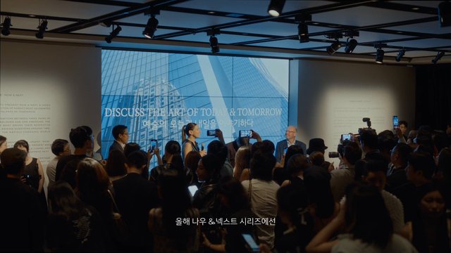Video Reference: indoor event, presentation, crowd, audience, stage, microphone, screen, conference, gallery, business event, speaker, projector, building, night, Korean text, English text