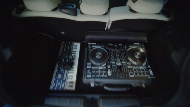 Video Reference: car trunk, cargo area, DJ controller, mixer, keyboard, music equipment, electronic gear, portable case, cables, automotive interior, transport, audio gear