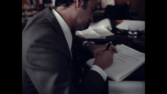 Video Reference: man, suit, writing, paperwork, meeting, office, table, document, pen, indoor, business, close-up, formal, work