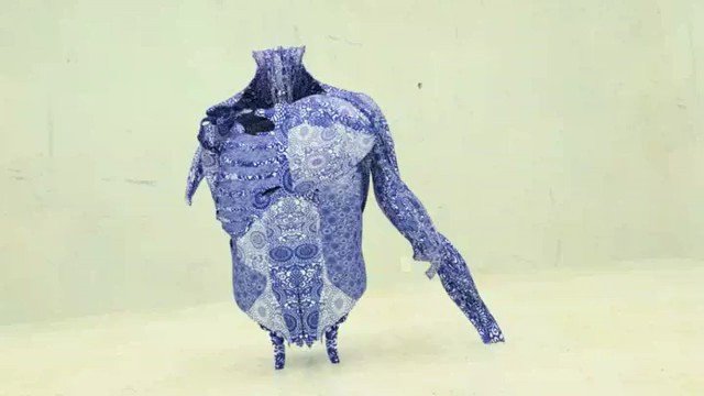 Video Reference: abstract, blue, patterned, humanoid, garment, suit, figure, standing, arm extended, design, texture, fabric, isolated, plain background