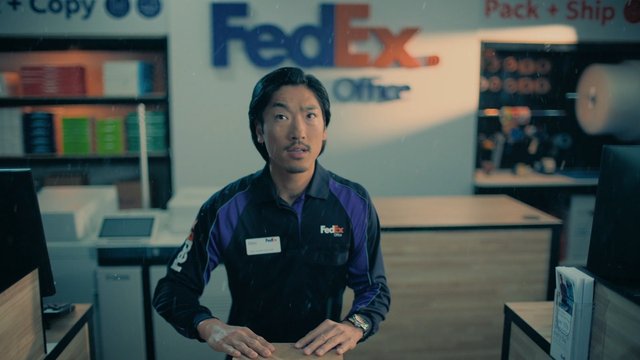 Video Reference: man, store, counter, uniform, retail, FedEx, shipping, office, service, indoor, customer service, workspace, employee, signage, business