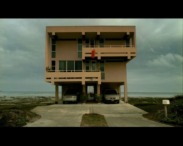 Video Reference: beach house, ocean, coastal, modern architecture, residential building, driveway, parked cars, cloudy sky, seaside, balcony, house exterior, waterfront