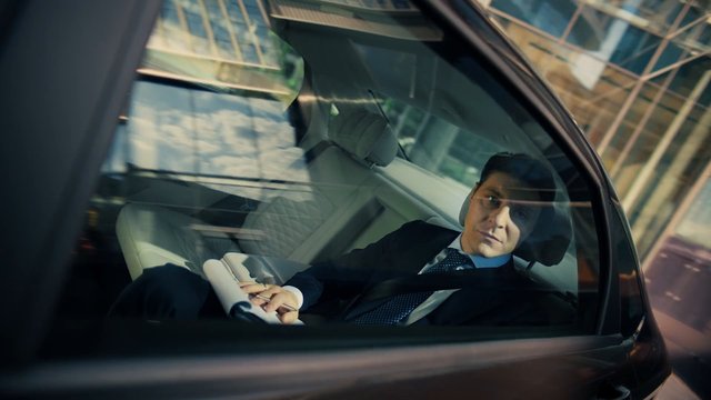 Video Reference: man, suit, car interior, back seat, window reflection, business, travel, vehicle, urban, close-up, portrait, luxury, commute