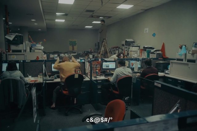 Video Reference: office, cubicles, workplace, computers, employees, desks, ladder, indoor, open plan, monitor, office supplies, busy office, standing person, seated workers, subtitle, interior
