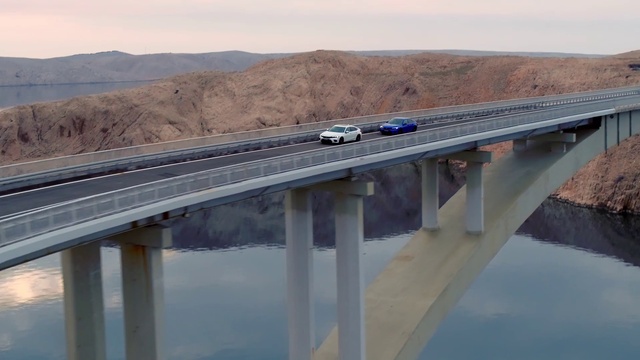 Video Reference: Water, Sky, Car, Road surface, Girder bridge, Thoroughfare, Road, Asphalt, Vehicle, Composite material