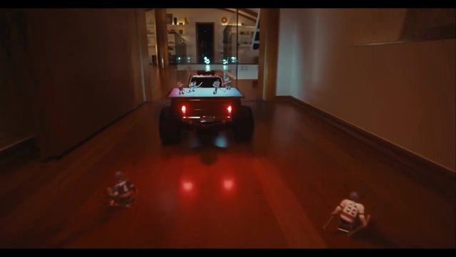 Video Reference: toy truck, remote control, hallway, indoor, night, floor, red lights, miniature figures, playroom, vehicle, motion, low light, camera following, toy car