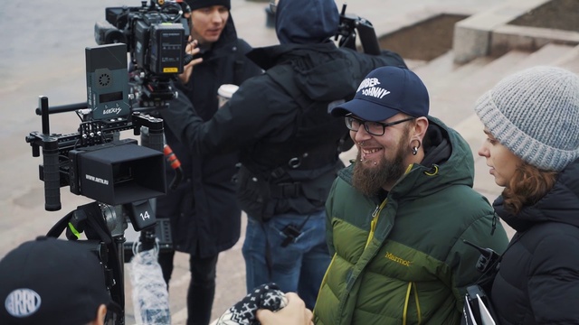Video Reference: Outerwear, Videographer, Smile, Camera, Film crew, Cap, Jacket, Television crew, Baseball cap, Cinematographer