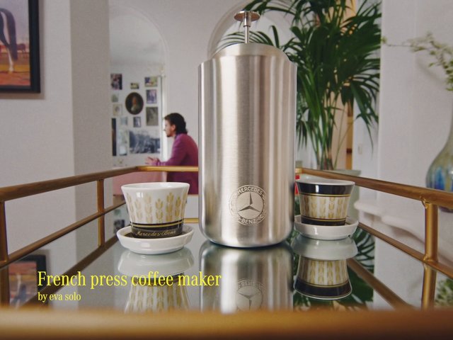Video Reference: french press, coffee maker, espresso cups, stainless steel, indoor, tabletop, mirror reflection, home decor, beverage, kitchenware, still life, blurred background, text overlay, luxury item