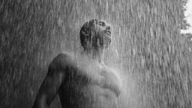 Video Reference: black and white, man, shirtless, water, shower, rain, outdoors, head tilted up, portrait, dramatic, nature, wet, streaming water