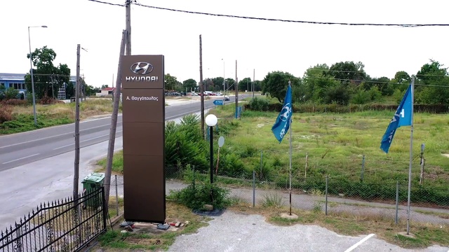 Video Reference: Sky, Plant, Flag, Tree, Land lot, Road surface, Asphalt, Fence, Grass, Sidewalk