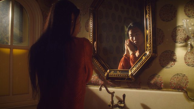 Video Reference: bathroom, mirror, reflection, woman, sink, indoor, warm light, ornate decor, getting ready, home interior, portrait, fashion, long hair, quiet scene