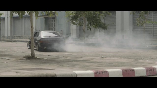 Video Reference: car, drifting, skid, tire smoke, street, urban, motion, vehicle, road, outdoors, action, stunt, empty street, curb, trees