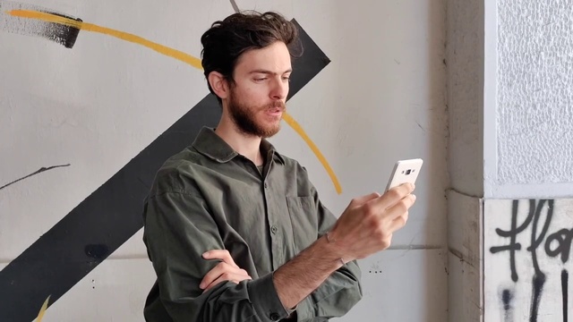 Video Reference: Hand, Shoulder, Sleeve, Standing, Eyewear, Gesture, Beard, Audio equipment, Street fashion, Technology