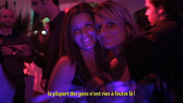 Video Reference: nightclub, party, crowd, women, smiling, low light, purple lighting, pink lighting, social event, indoor, people, subtitles, French text, dance floor, nightlife