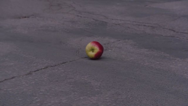 Video Reference: apple, fruit, pavement, road, ground, outdoor, still life, single object