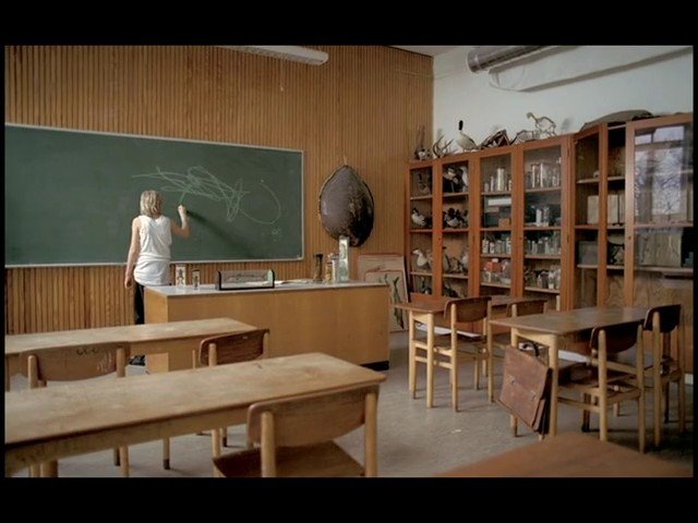Video Reference: classroom, chalkboard, desks, teacher, empty room, wooden furniture, cabinet, education, interior, writing, school, standing, chalk, old classroom