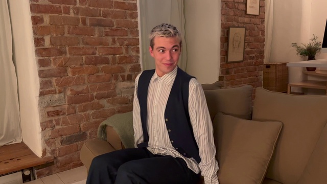 Video Reference: Furniture, Smile, Comfort, Neck, Sleeve, Flash photography, Dress shirt, Wood, Houseplant, Blazer
