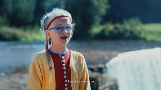 Video Reference: girl, child, glasses, braids, outdoor, water, nature, portrait, speaking, subtitles, daylight, colorful clothing