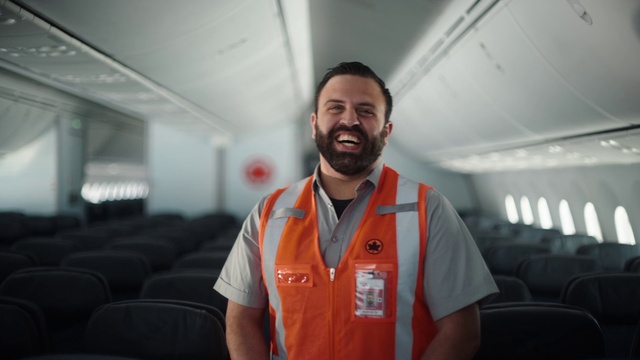 Video Reference: Smile, Sleeve, Beard, Collar, Aircraft cabin, Air travel, Travel, T-shirt, Engineering, Aerospace engineering