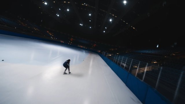 Video Reference: ice skating, indoor rink, skater, sports, arena, winter sport, motion blur, training, empty stadium, ice rink, athlete, night, overhead lights