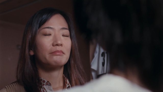 Video Reference: woman, close-up, indoor, dim light, eyes closed, portrait, blurred foreground, conversation, interior, face, emotional, soft focus