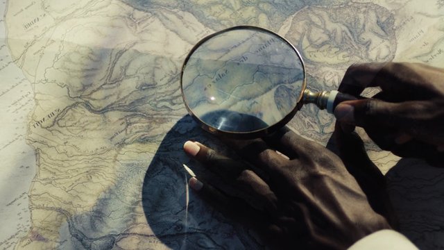 Video Reference: magnifying glass, map, topographic map, hands, searching, navigation, exploration, detail, close-up, paper map, adventure, investigation