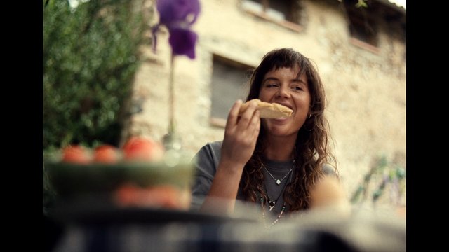 Video Reference: woman, eating, bread, outdoors, smiling, portrait, candid, casual, food, blurred background, natural light, close-up, street, lifestyle