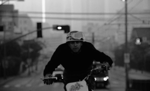 Video Reference: black and white, cyclist, bike, street, urban, motion blur, helmet, traffic, city, rider, outdoors, vehicle, commute, gritty, portrait