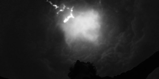 Video Reference: dark, night, silhouette, person, arms raised, bright light, glare, clouds, smoke, backlit, outdoors, low light