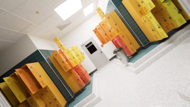 Video Reference: locker room, school, lockers, hallway, interior, empty, tiled floor, tiled walls, ceiling lights, door, trash can, yellow lockers, orange lockers, corridor, indoor