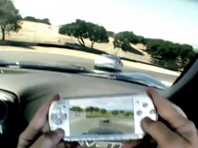 Video Reference: handheld console, gaming device, car interior, driving, road, windshield view, video game, hands, mobile gaming, travel, motion blur, outdoor, vehicle, screen