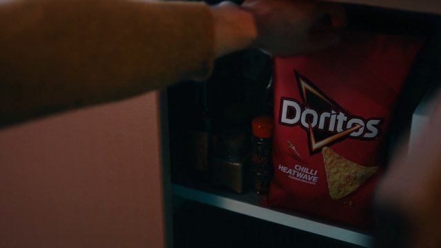 Video Reference: snack, chips, potato chips, packaging, shelf, close-up, indoor, food, red bag, convenience, pantry, blurred foreground