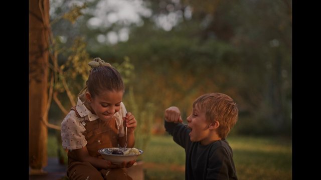 Video Reference: children, outdoors, dessert, sharing, siblings, garden, family, snack, smiling, summer, candid, togetherness, food, playful, lifestyle, natural light