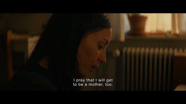 Video Reference: woman, profile, close-up, indoor, dimly lit, subtitles, melancholy, drama, interior, warm lighting, portrait, side view