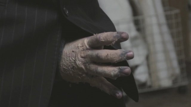 Video Reference: hand, close-up, dirty hand, weathered, coat, jacket, dim light, indoor, gritty, texture, human hand, clothing, low light, dramatic, cinematic