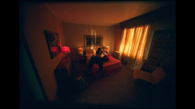 Video Reference: bedroom, interior, bed, person, sunlight, curtains, lamp, warm light, wide angle, home, room, window, furniture, evening, moody, indoor