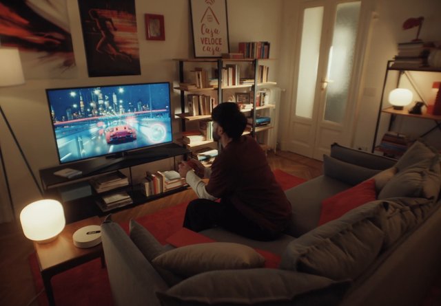 Video Reference: living room, person, video game, gaming, television, sofa, home interior, night, bookshelf, lamp, couch, racing game, entertainment, cozy, modern apartment