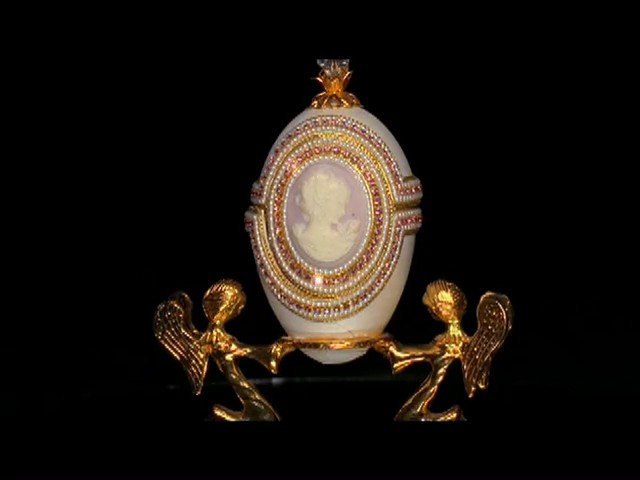 Video Reference: jeweled, ornate, decorative object, oval, stand, gold, gemstone, luxury, antique style, display, black background, centered, embellished